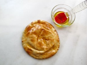 Brushing pita rounds with olive oil.